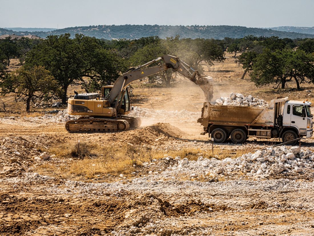 Excavator and dump truck moving dirt on an Austin, TX site